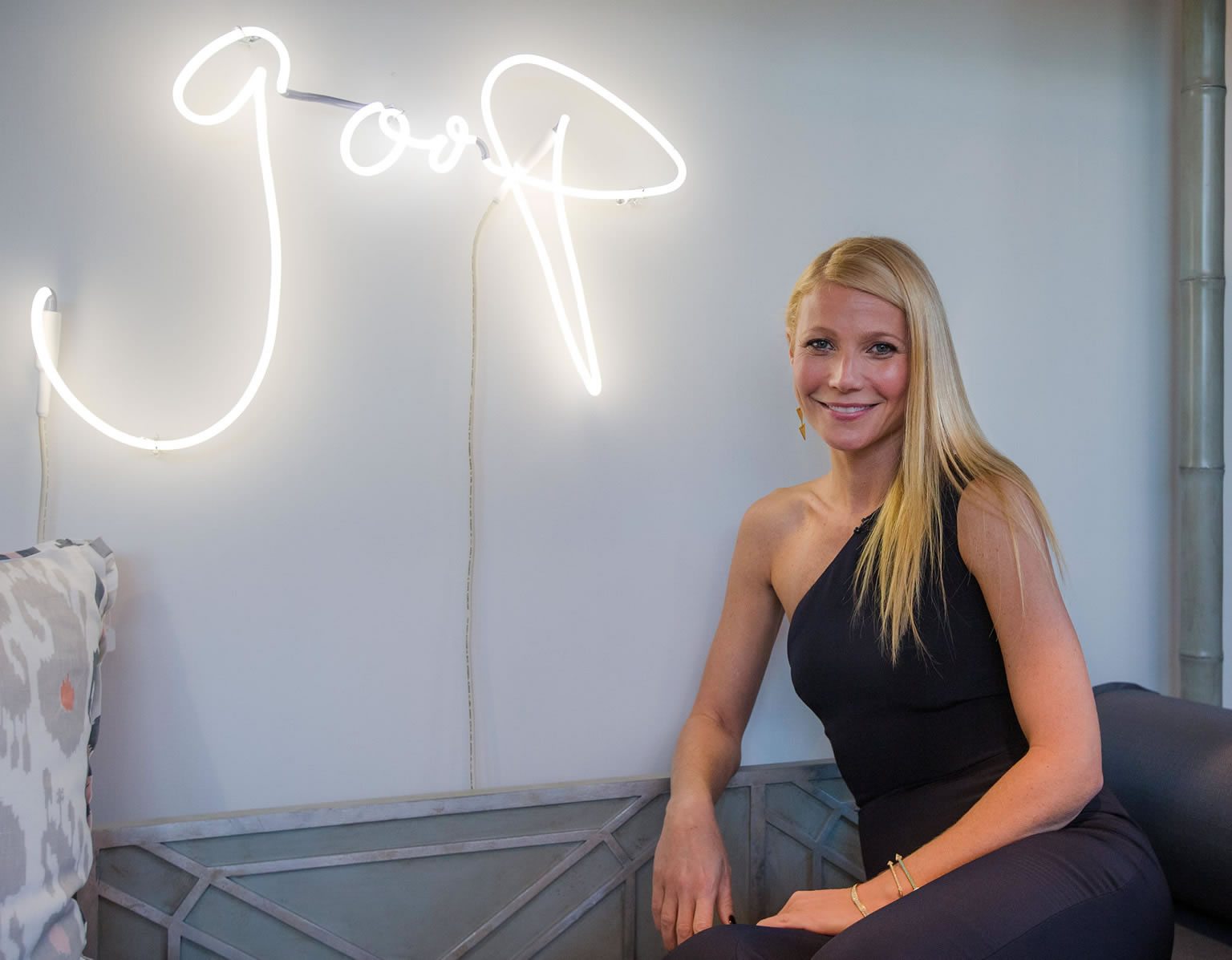 Gwyneth Paltrow posing proudly in front of a neon goop logo. Somehow this seems appropriate.