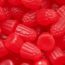 Close-up of assorted red gummy candies with various textures and shapes, resembling berries and fruit.