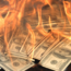 A stack of hundred-dollar bills is engulfed in bright orange flames, creating a dramatic and intense scene symbolizing financial loss or waste.