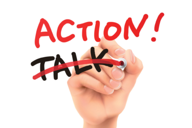 A hand holding a red marker crosses out the word "TALK" and writes "ACTION!" in red, capital letters. The message emphasizes action over talk, symbolizing taking initiative and making changes. The background is white.