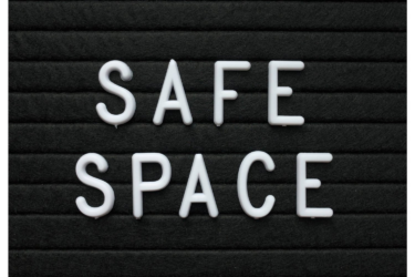 White plastic letters on a black felt letter board spell out "SAFE SPACE" in two lines, with a simple and clean design.