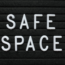 White plastic letters on a black felt letter board spell out "SAFE SPACE" in two lines, with a simple and clean design.