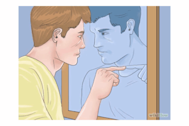 A person in a yellow shirt stands closely in front of a mirror, touching the glass and looking intently at their own reflection, which appears thoughtful.