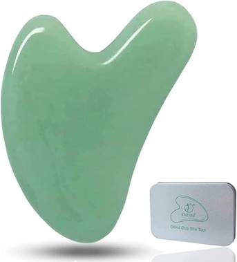A green jade gua sha facial massage tool next to a small rectangular storage case with a matching gua sha design printed on the lid.