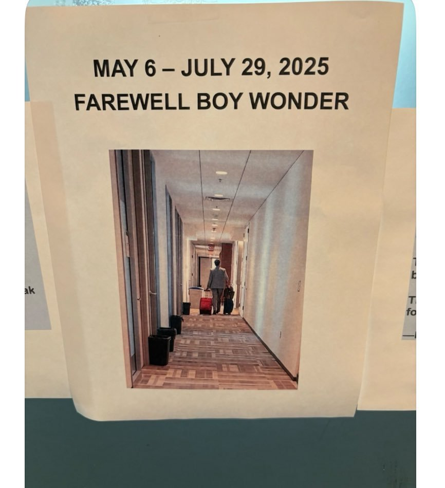 A printed sign reads "MAY 6 – JULY 29, 2025 FAREWELL BOY WONDER" above a photo of a person walking down a hallway with luggage. The sign is posted on a wall.