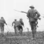 World War I soldiers wearing helmets and carrying rifles advance through a barbed wire field, moving forward in formation on a battlefield.