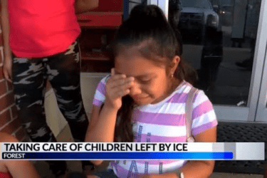 Young girl wipes her eyes while sitting outside a building. Text reads, “Taking care of children left by ICE.” Other children and an adult are partially visible nearby.
