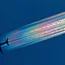 A commercial airplane in flight, leaving a bright, iridescent rainbow-colored contrail against a deep blue sky.