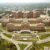 Aerial view of a large, multi-winged brick hospital complex surrounded by parking lots and wooded grounds.